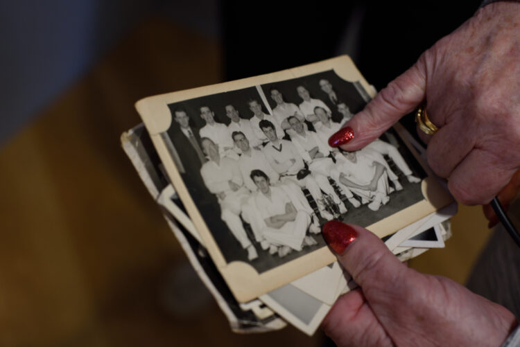 older ladies hands with red painted fingernails holding black and white photo of a sports team