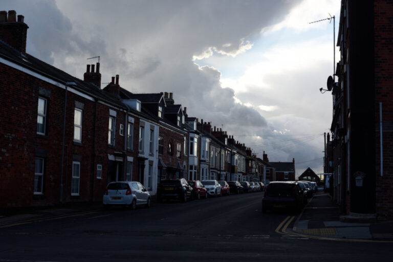 terraced street with cloudy sky overhead and chink of sunlight