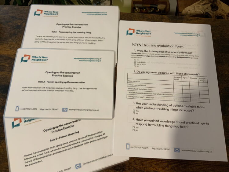 a photograph of printed resources and feedback forms for use at a Who is Your Neighbour event